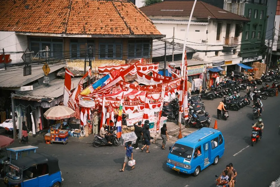 Colorful street market scene in Jakarta, Indonesia, displaying red and white flags amidst busy traffic.