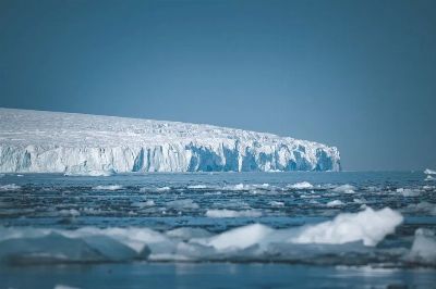 A vast icy landscape with towering icebergs and a serene, calm sea in Antarctica.