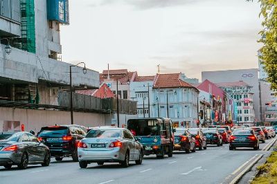Traffic scene in Singapore's historic Chinatown with traditional shophouses and modern buildings.