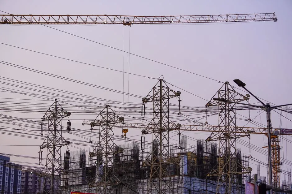 Construction site with cranes and power lines in Mumbai during evening hours.