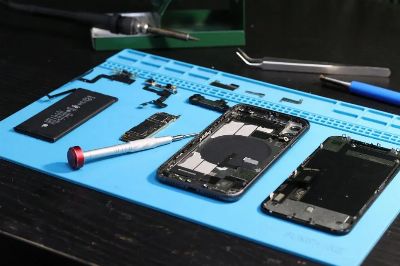 Close-up of disassembled smartphone parts on a blue repair mat with tools.