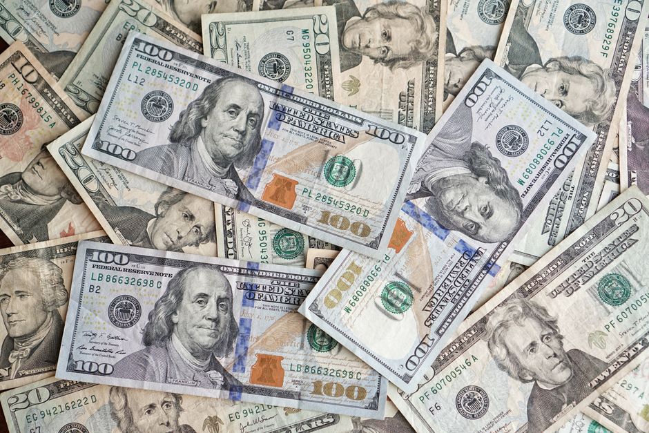 A close-up view of scattered US dollar bills showcasing various denominations and presidents.
