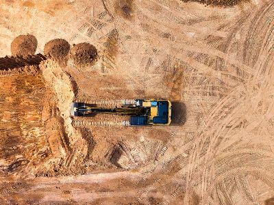 Aerial photo of an excavator working on a large empty construction site.