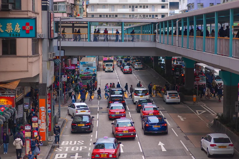 Traffic and pedestrians on a street in Hong Kong, seen from a footbridge