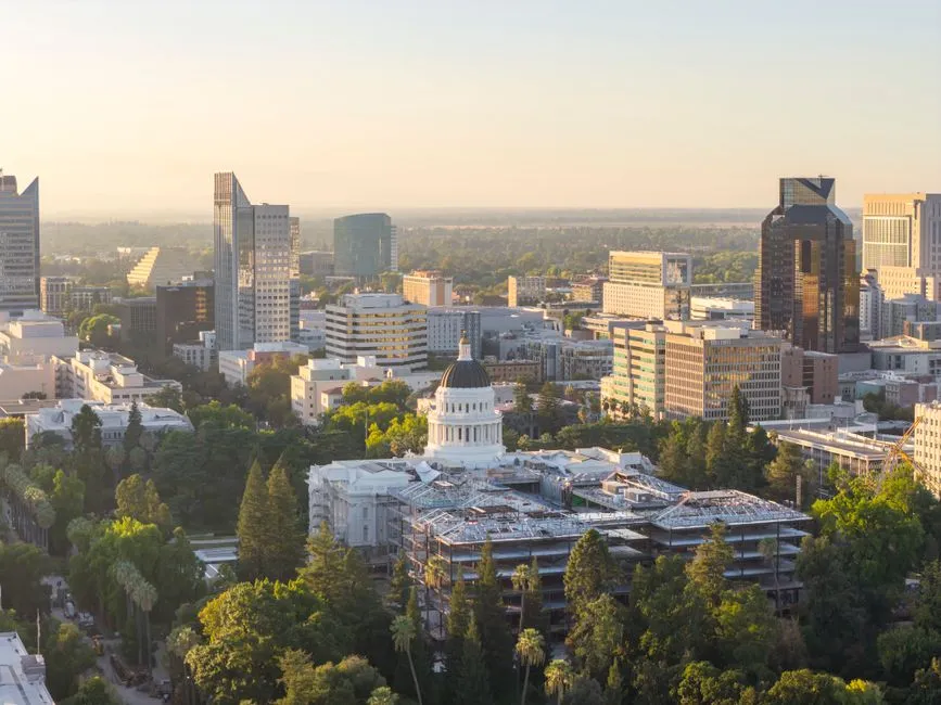 The Sacramento skyline at dusk, with the white dome of the California State Capitol rising among the trees.