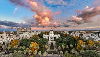 Dramatic sunset over Sacramento's California State Capitol, showcasing autumn colors and a vibrant sky.