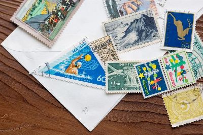A variety of vintage postage stamps from around the world on an envelope, displayed on a wooden surface.