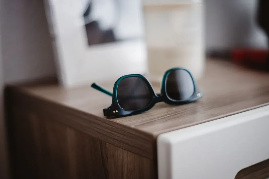 A pair of unbranded dark glasses folded on a wooden surface — illustrative; camera glasses are built to be indistinguishable from ordinary eyewear.