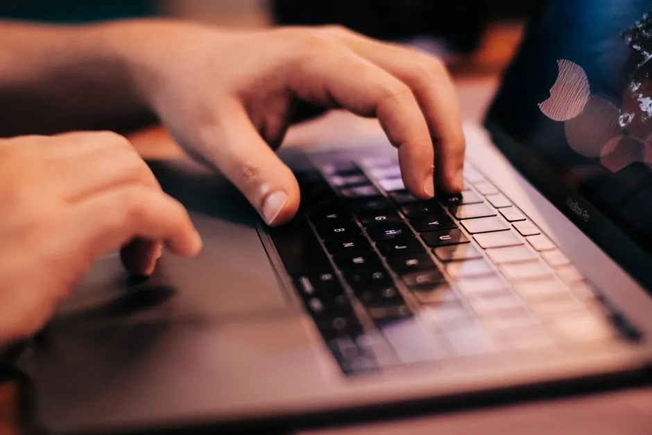 Hands typing on a laptop keyboard