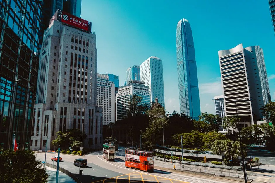 Hong Kong's Central district on a clear day: two double-decker trams on the road below, the old Bank of China building on the left and the tapered tower of Two IFC behind