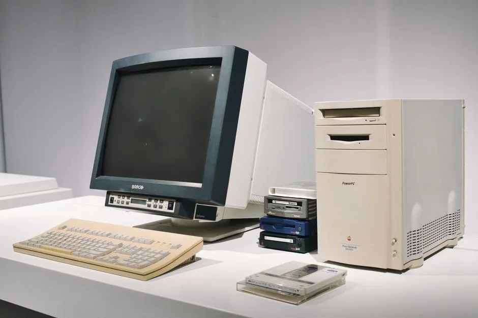 An older beige desktop computer with a CRT monitor, tower and keyboard arranged on a white surface