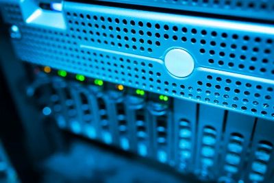 Focused view of a modern data server rack with blinking lights in a blue-lit environment.