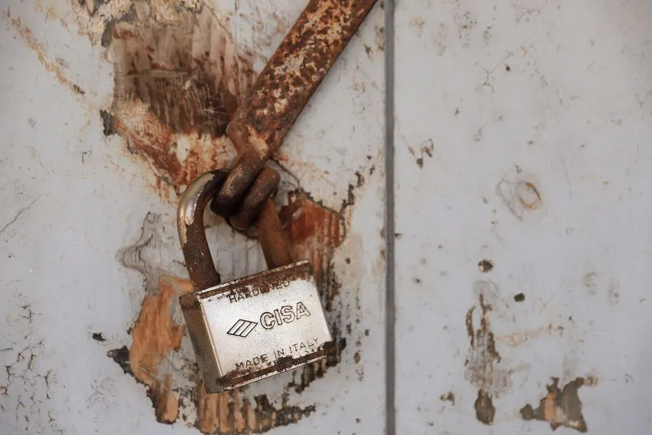 Detailed shot of a rusty padlock on a weathered door conveying security and time passage.