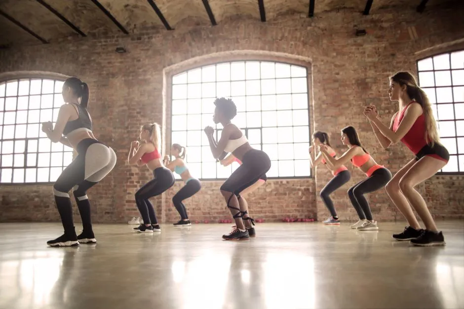 A group exercise class mid-squat in a studio — illustrating the booking waitlist an AI agent manipulated on its user's behalf.