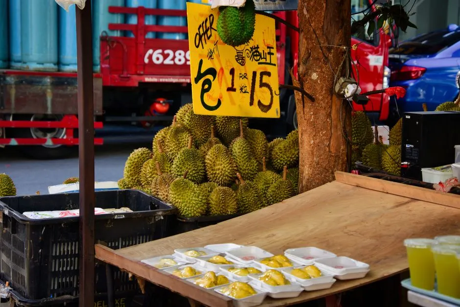 A fruit stall piled with durians under a hand-written price sign