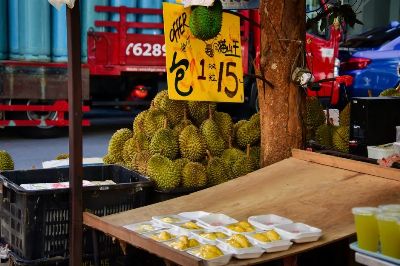 Vibrant market stall selling fresh durians with enticing offer in Singapore street. Authentic local flavor.
