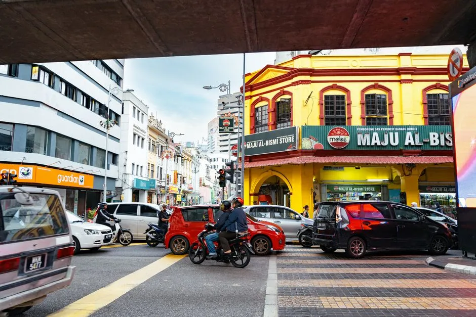 Cars and motorcycles at a junction lined with old shophouses in Malaysia