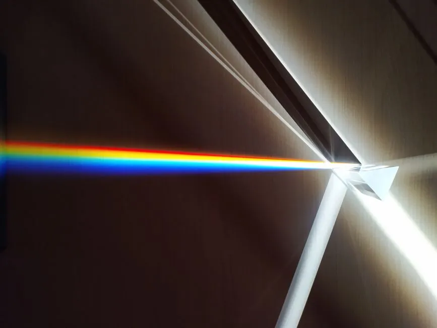 A glass prism splitting a beam of white light into a visible spectrum, illustrating a report on low-loss optical waveguides fabricated on a silicon chip.