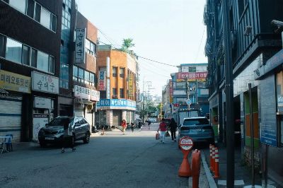 A typical bustling street in Seoul with people and cars amidst urban buildings reflecting local culture.