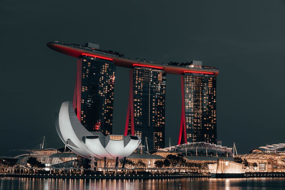 Dramatic night view of Marina Bay Sands, Singapore, with glowing cityscape and reflection.