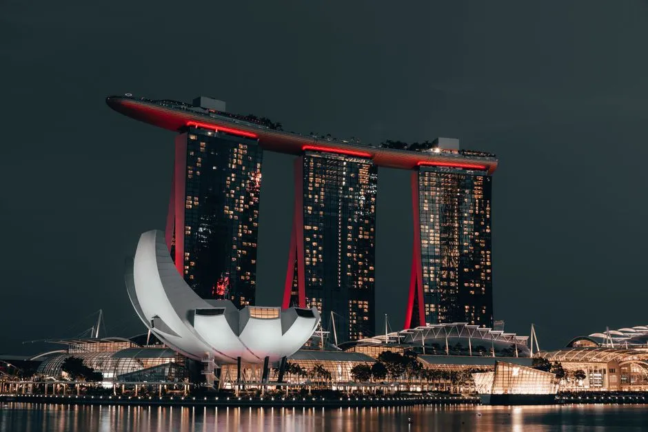 Dramatic night view of Marina Bay Sands, Singapore, with glowing cityscape and reflection.