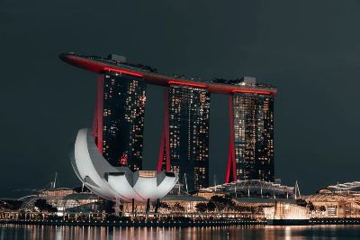 Dramatic night view of Marina Bay Sands, Singapore, with glowing cityscape and reflection.
