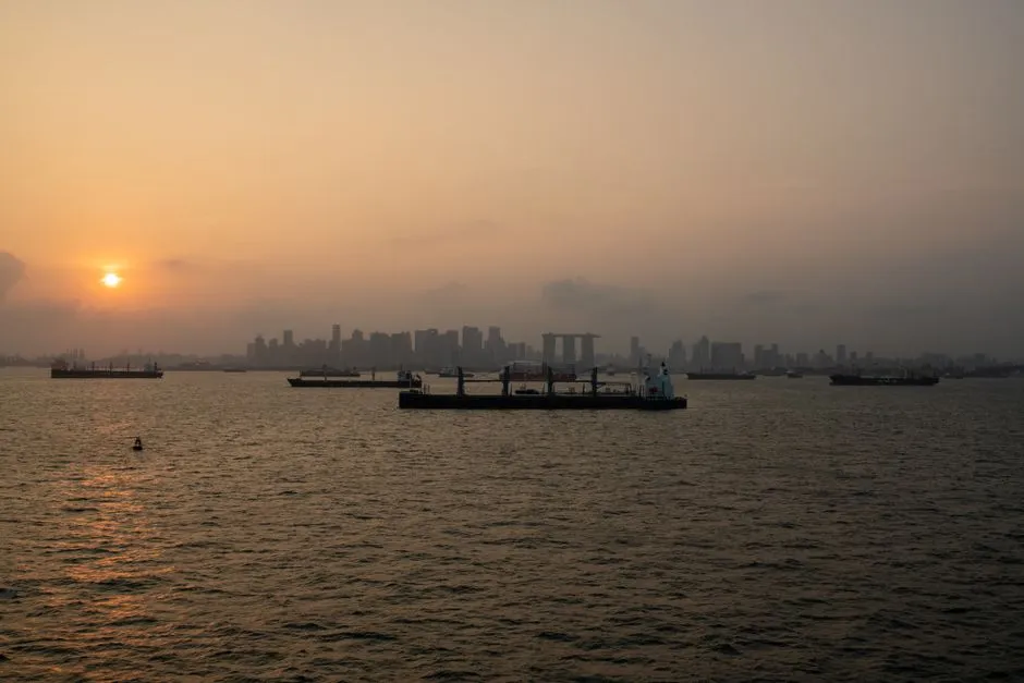 Singapore's skyline, including Marina Bay Sands, seen across anchored ships under a hazy orange sky (file photo)