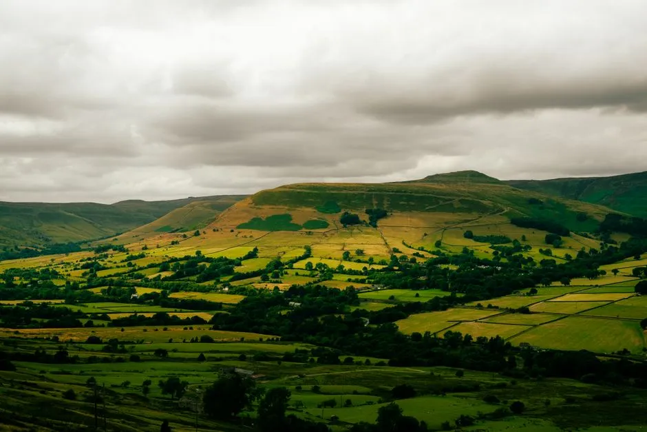 Green hills and a patchwork of fields under a cloudy sky