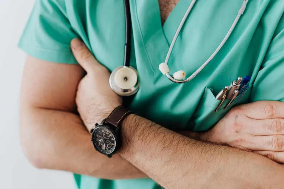 A clinician in green scrubs with arms folded and a stethoscope around the neck