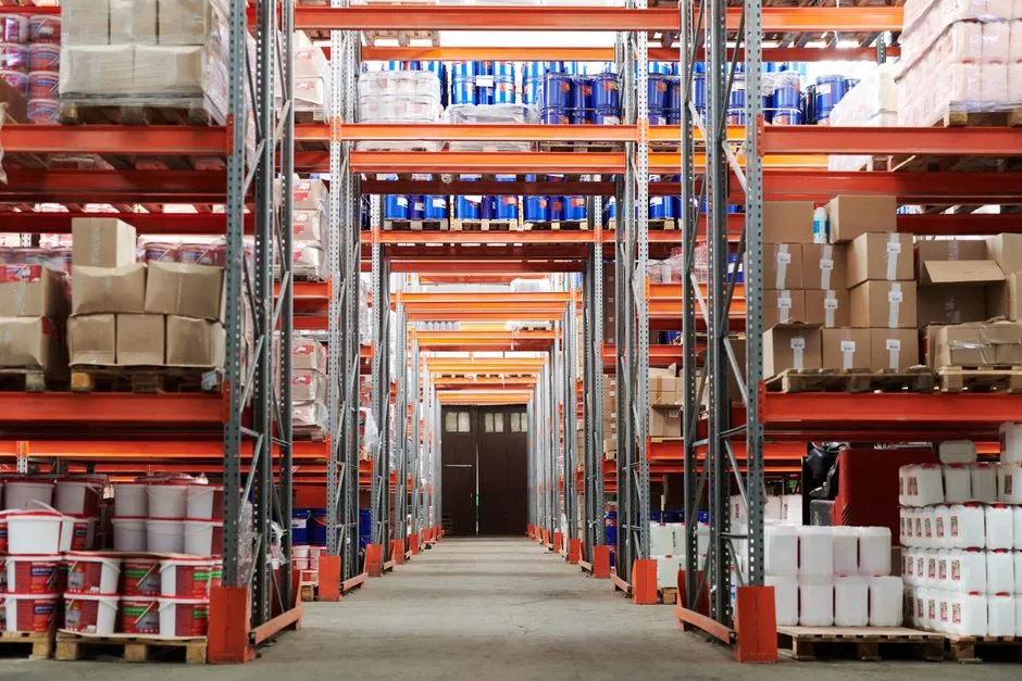 A warehouse aisle between tall pallet racks stacked with boxes