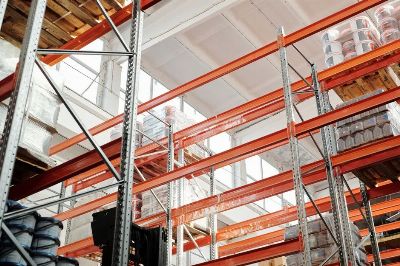 Bright warehouse interior with orange metal shelving units and stored goods.