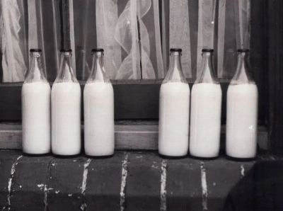 Vintage photo of glass milk bottles on a brick windowsill in monochrome.