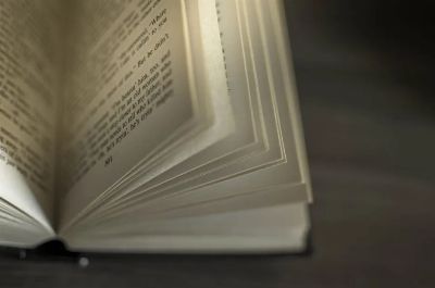 A close-up image of an open book with visible text, showcasing turning pages.