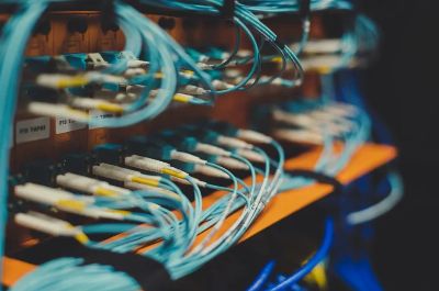 Closeup of many cables with blue wires plugged in modern switch with similar adapters on blurred background in modern studio