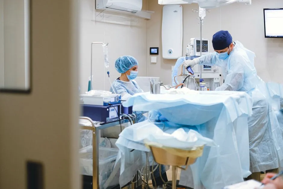 Masked surgical staff at work around a draped patient in an operating theatre