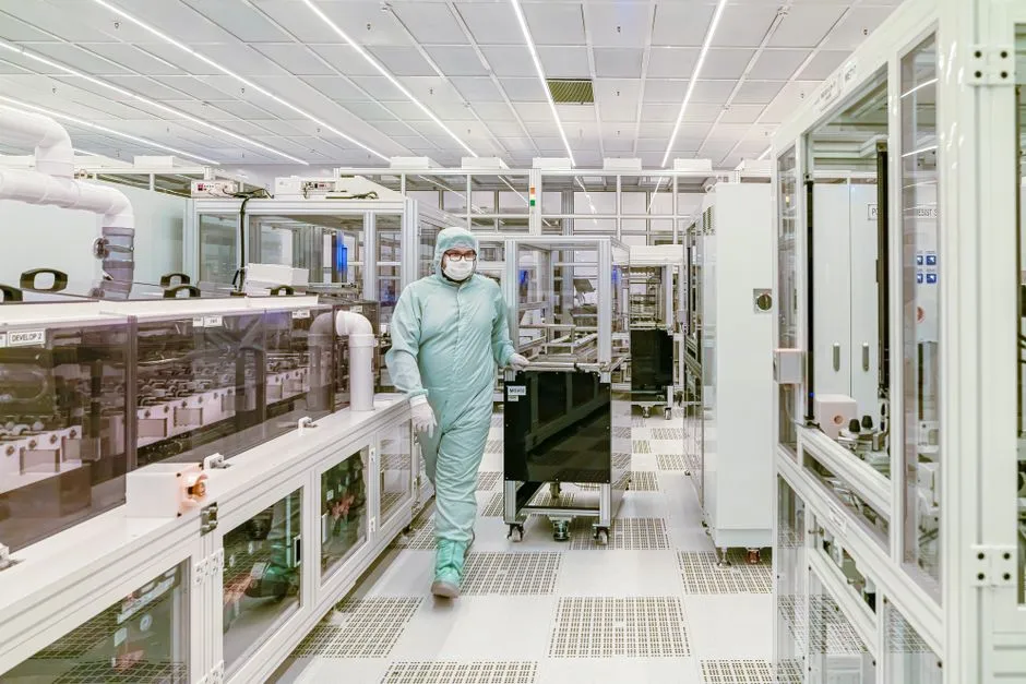 A technician in protective clothing inside a cleanroom, illustrating a report on Applied Materials and chipmaking equipment demand.