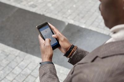 A stylish professional adult using a smartphone with a navigation app on an urban street.