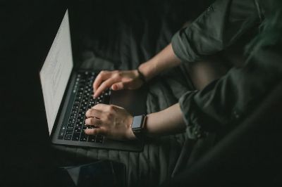 Hands typing on a laptop in a dark setting, technology and focus concept.