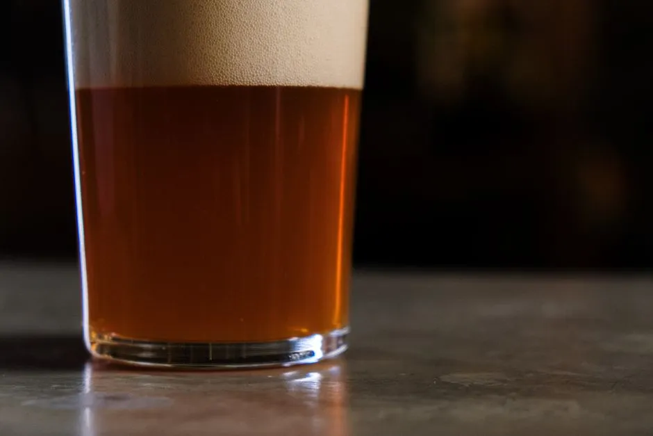 A glass of amber beer on a dark table