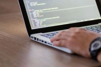 Person coding on a laptop with HTML code on screen, showcasing development work.