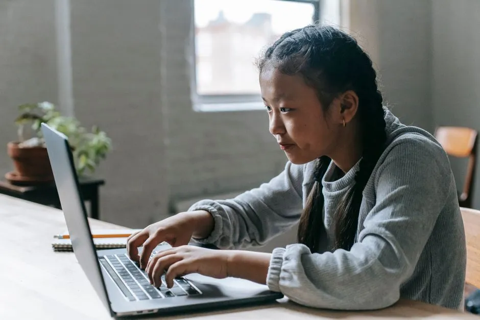 A girl working on a laptop at a table; the states' suits centre on how chatbots treat young users