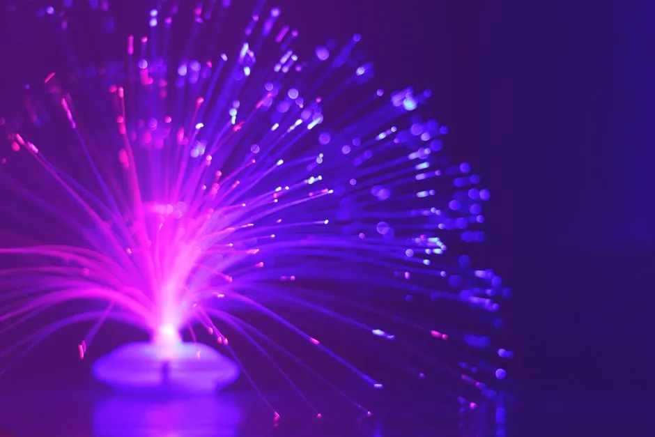 Hundreds of illuminated optical fibre strands fanning out from a single point against a dark background