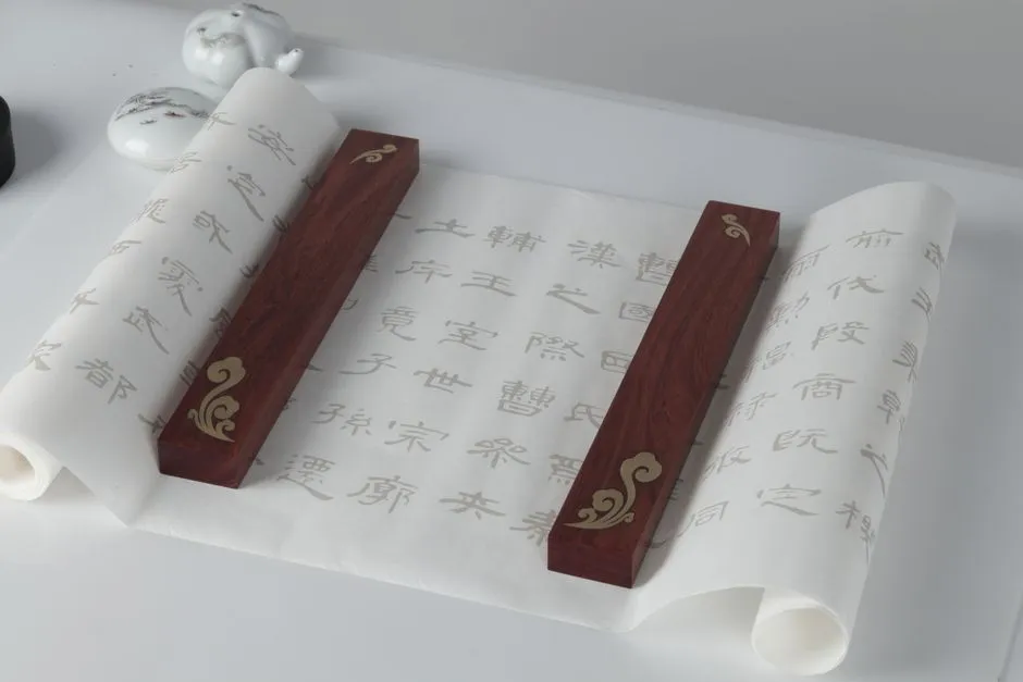 A scroll of Chinese characters held flat by two wooden paperweights