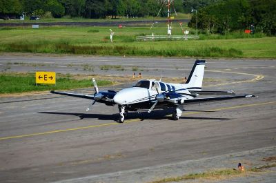 A small propeller aircraft on a quiet runway at a sunny airport.