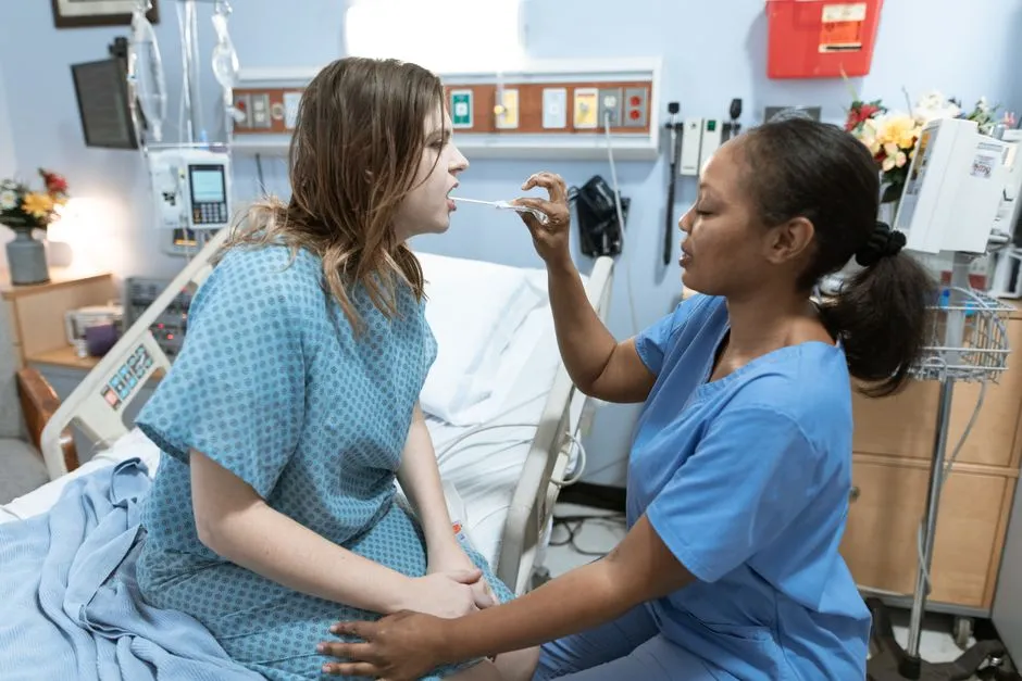 A nurse examines a patient sitting on a hospital bed