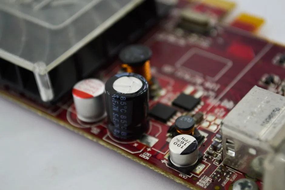 A close-up of a red circuit board crowded with capacitors and memory packages