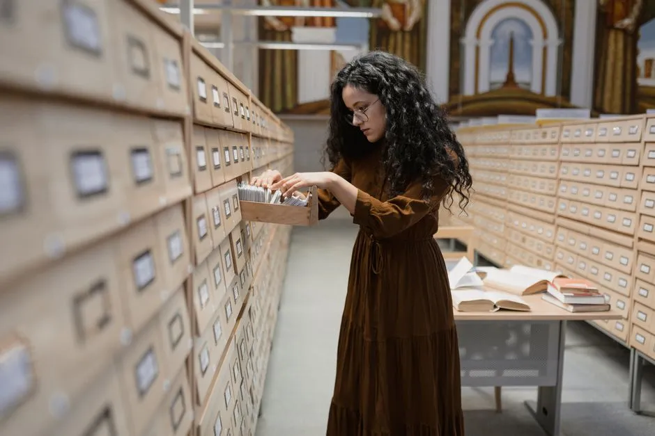 A woman searching a wall of library card-catalogue drawers, pulling one open — a filing system is only useful when its drawers match what is being filed.