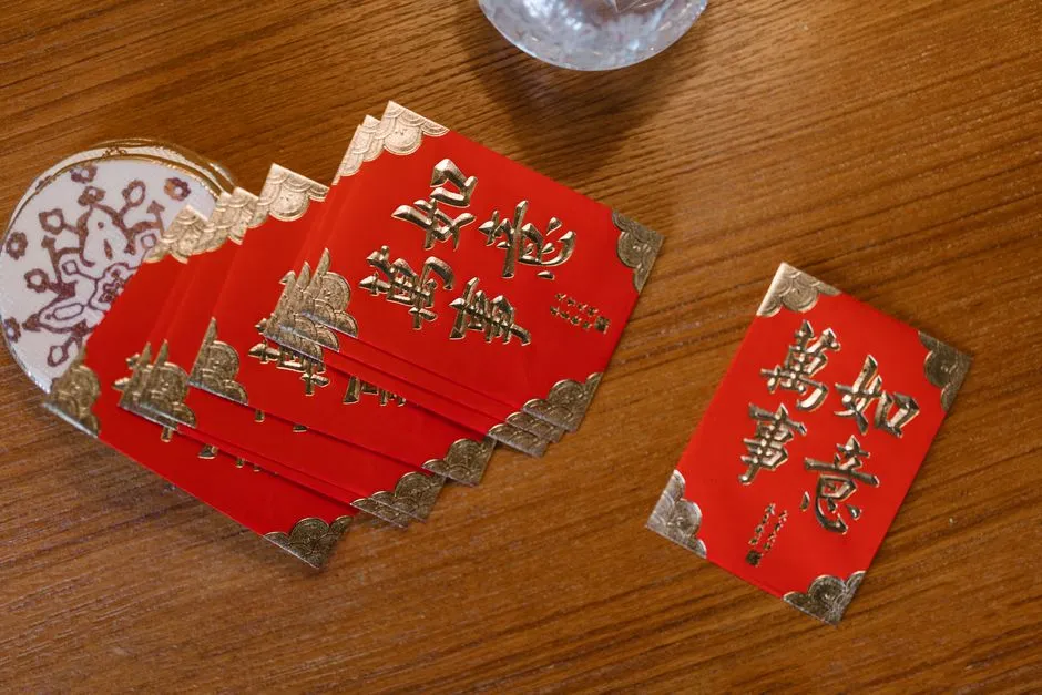 Red envelopes printed with gold characters spread on a wooden table