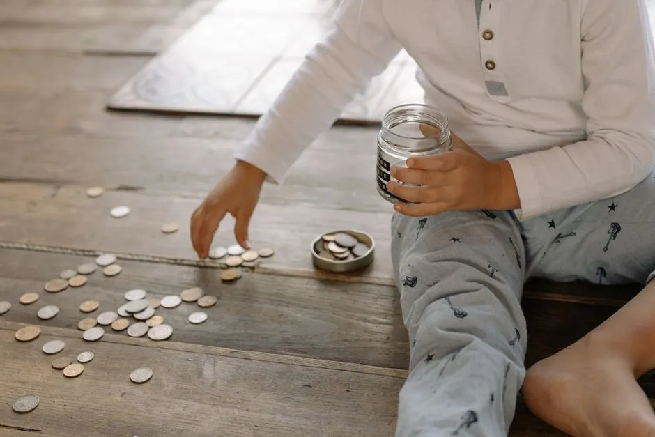 A child counting coins from a glass jar on a wooden floor