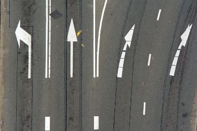 High-angle view of asphalt road with directional arrows and lane markings.